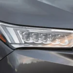 Cận cảnh đèn pha của mẫu xe SUV Acura MDX Sport Hybrid 2020 màu xám, minh họa một trong những dòng xe bị ảnh hưởng bởi đợt triệu hồi đèn chiếu sáng.