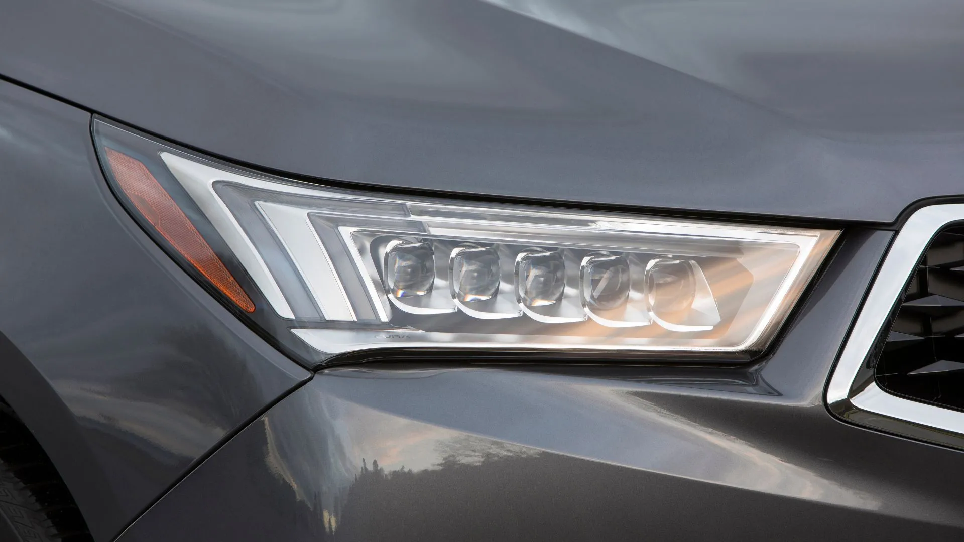 Cận cảnh đèn pha của mẫu xe SUV Acura MDX Sport Hybrid 2020 màu xám, minh họa một trong những dòng xe bị ảnh hưởng bởi đợt triệu hồi đèn chiếu sáng.