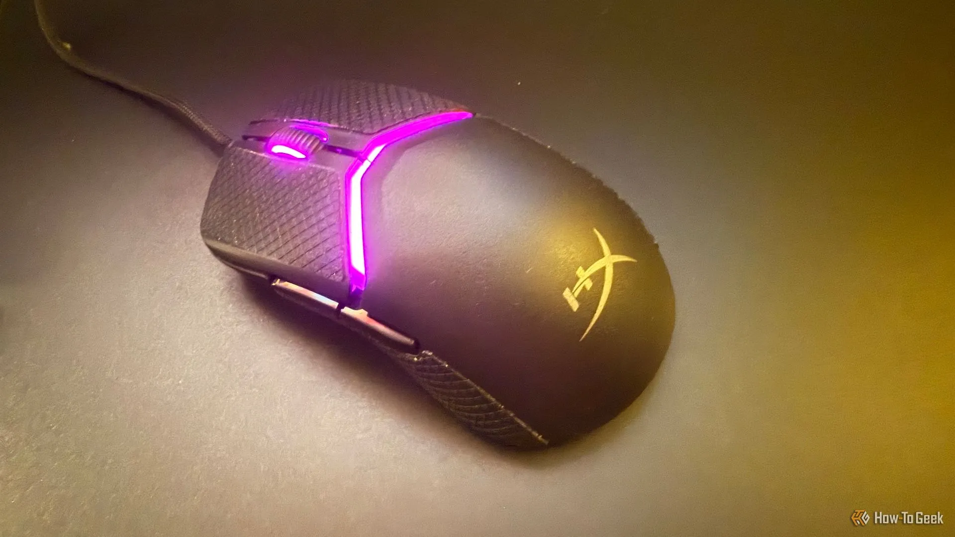 Chuột HyperX Pulsefire Saga đặt nghiêng trên bàn di chuột bằng kính, thể hiện sự mượt mà và nhẹ nhàng khi di chuyển