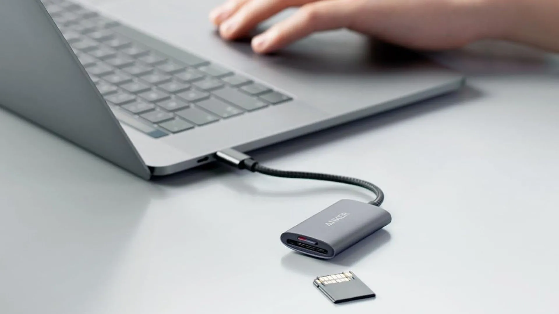 Đầu đọc thẻ Anker PowerExpand+ màu đen được cắm vào cổng USB-C của một chiếc máy tính xách tay màu bạc, sẵn sàng truyền dữ liệu.