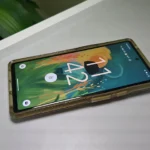 Điện thoại Google Pixel 6 màu xanh mint trong ốp lưng, đặt trên bàn làm việc, cho thấy sự cồng kềnh và che khuất thiết kế gốc.