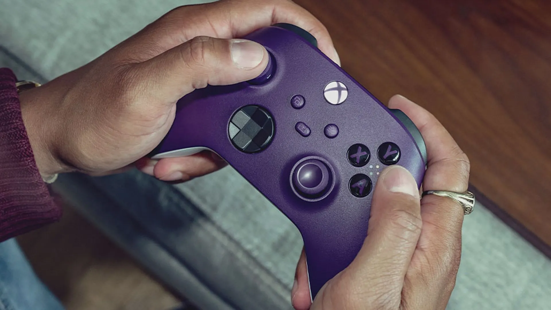 Đôi tay đang cầm bộ điều khiển không dây Xbox màu tím.