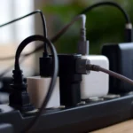 Hình ảnh nhiều củ sạc và cáp sạc USB đang được cắm vào ổ cắm điện, minh họa sự cần thiết của sạc đa cổng để giảm bớt sự lộn xộn trên bàn làm việc.