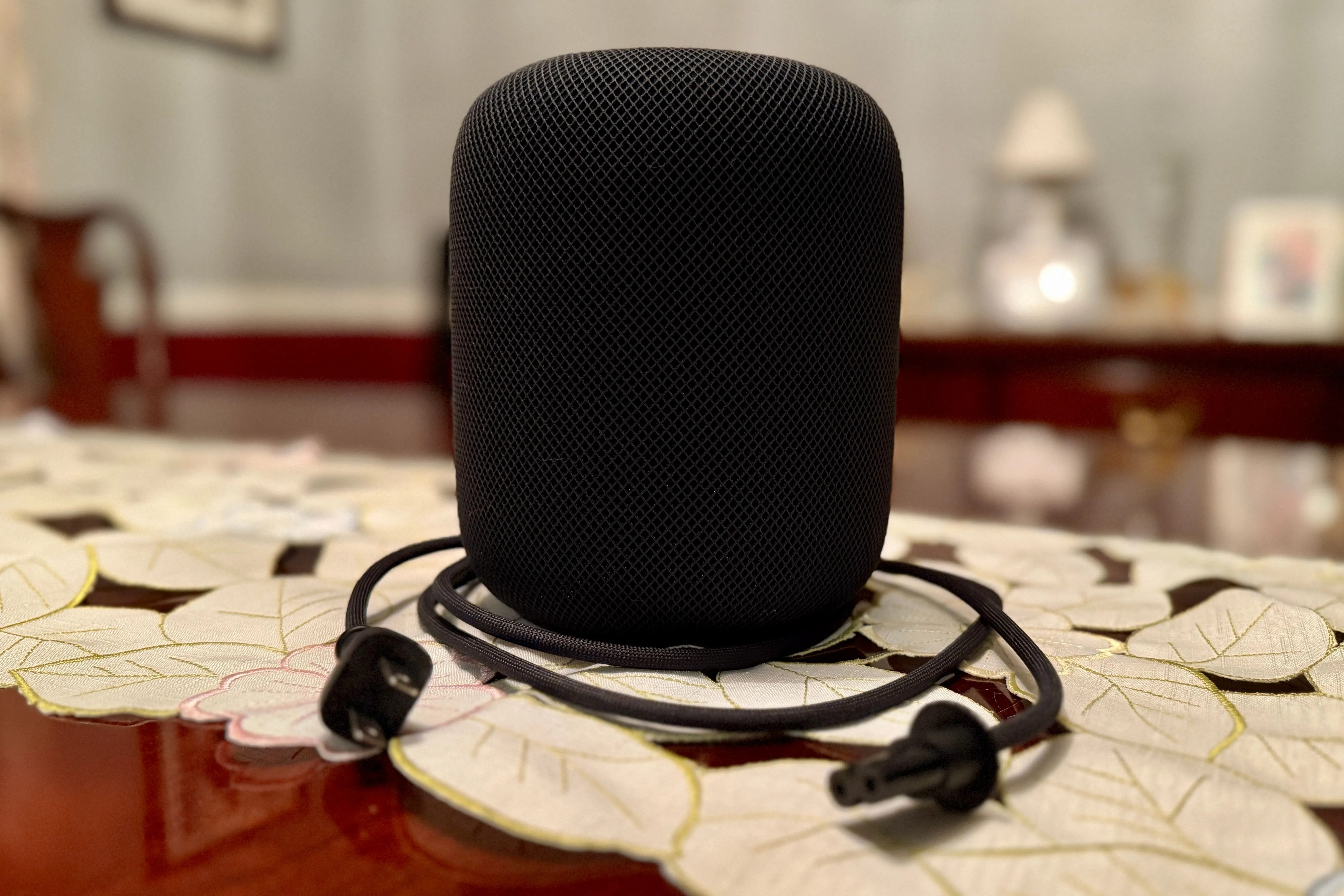 HomePod màu đen với cáp nguồn có thể tháo rời được cuộn lại gọn gàng.