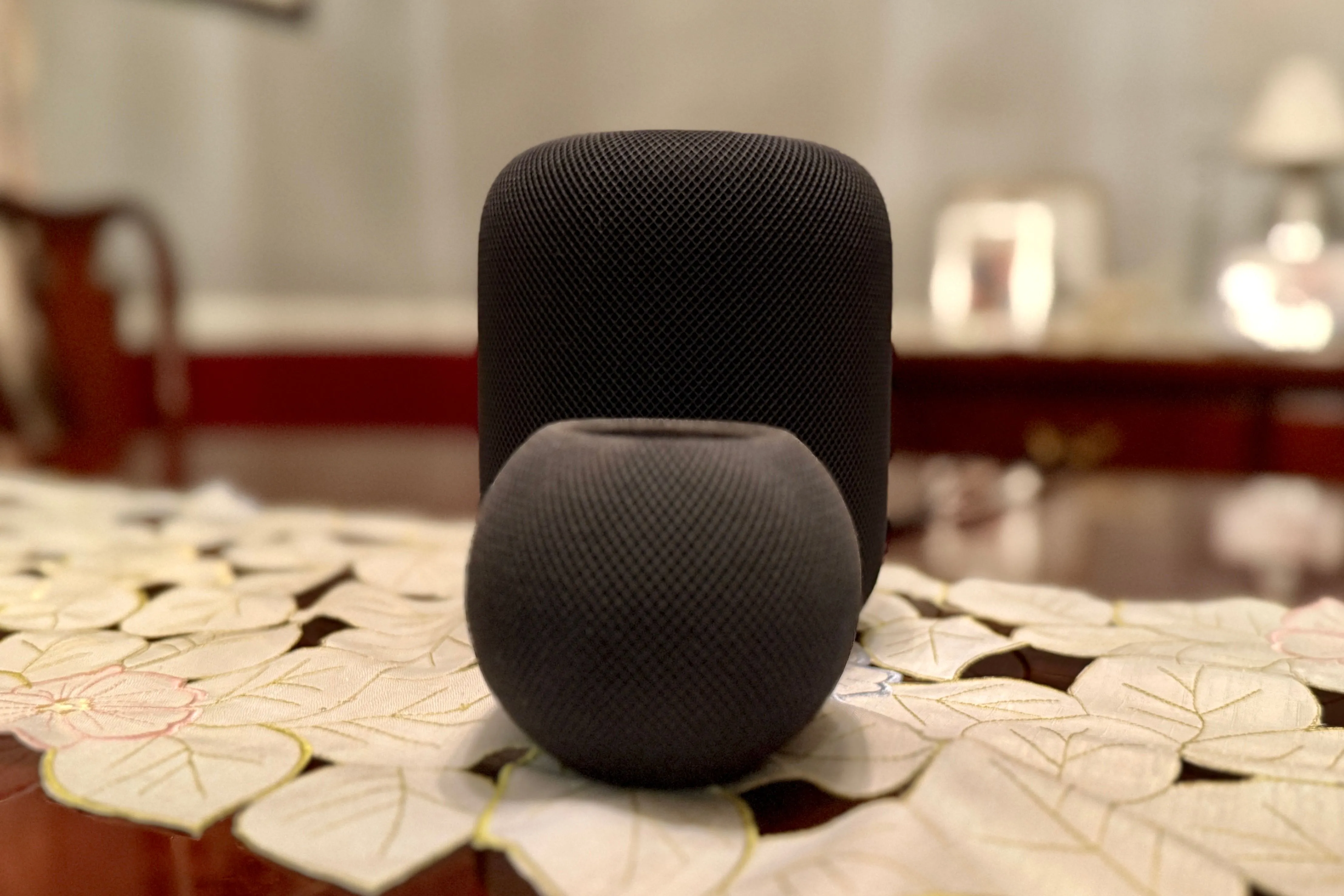 HomePod mini màu đen đặt phía trước HomePod kích thước đầy đủ để thể hiện sự khác biệt về kích thước.