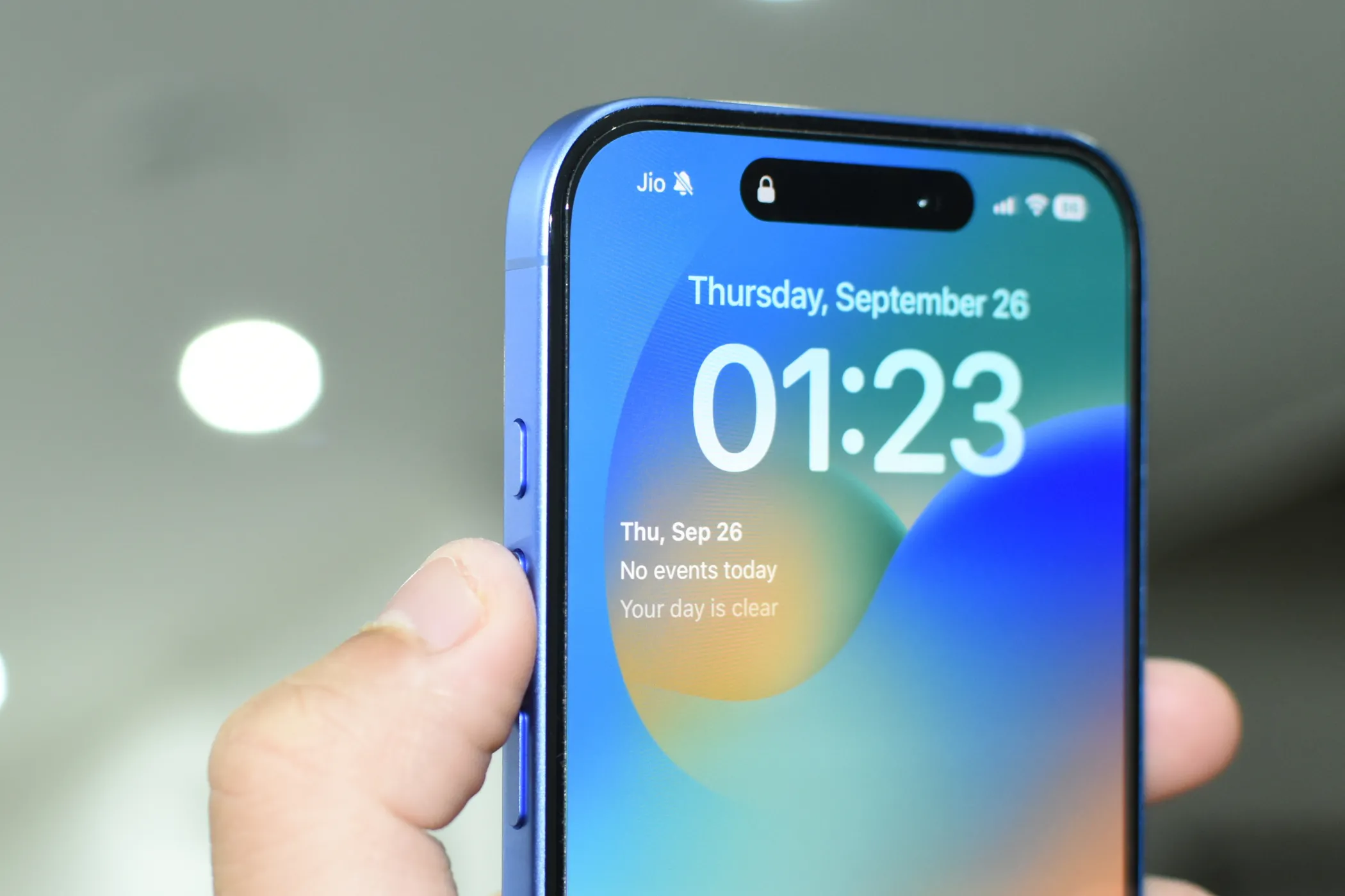 iPhone 16 màu Ultramarine với ngón tay chỉ vào Nút Tác vụ (Action Button), gợi ý tùy biến chế độ hoảng loạn.