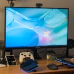 Màn hình chơi game GIGABYTE M32U 4K trên bàn làm việc với bàn phím, tay cầm và phụ kiện.