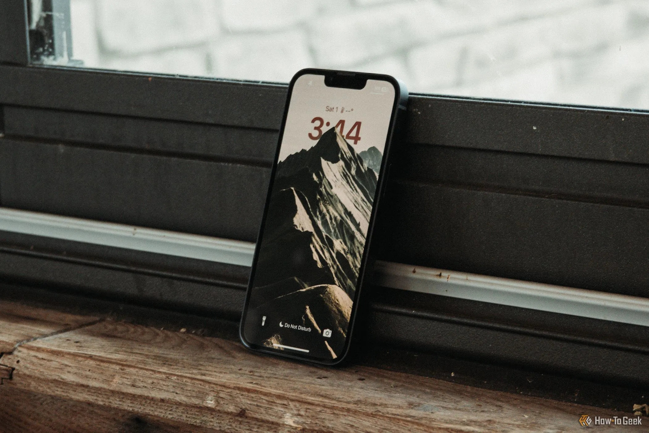 Màn hình khóa của iPhone 16e hiển thị đang nghiêng tựa vào cửa sổ, minh họa kích thước màn hình