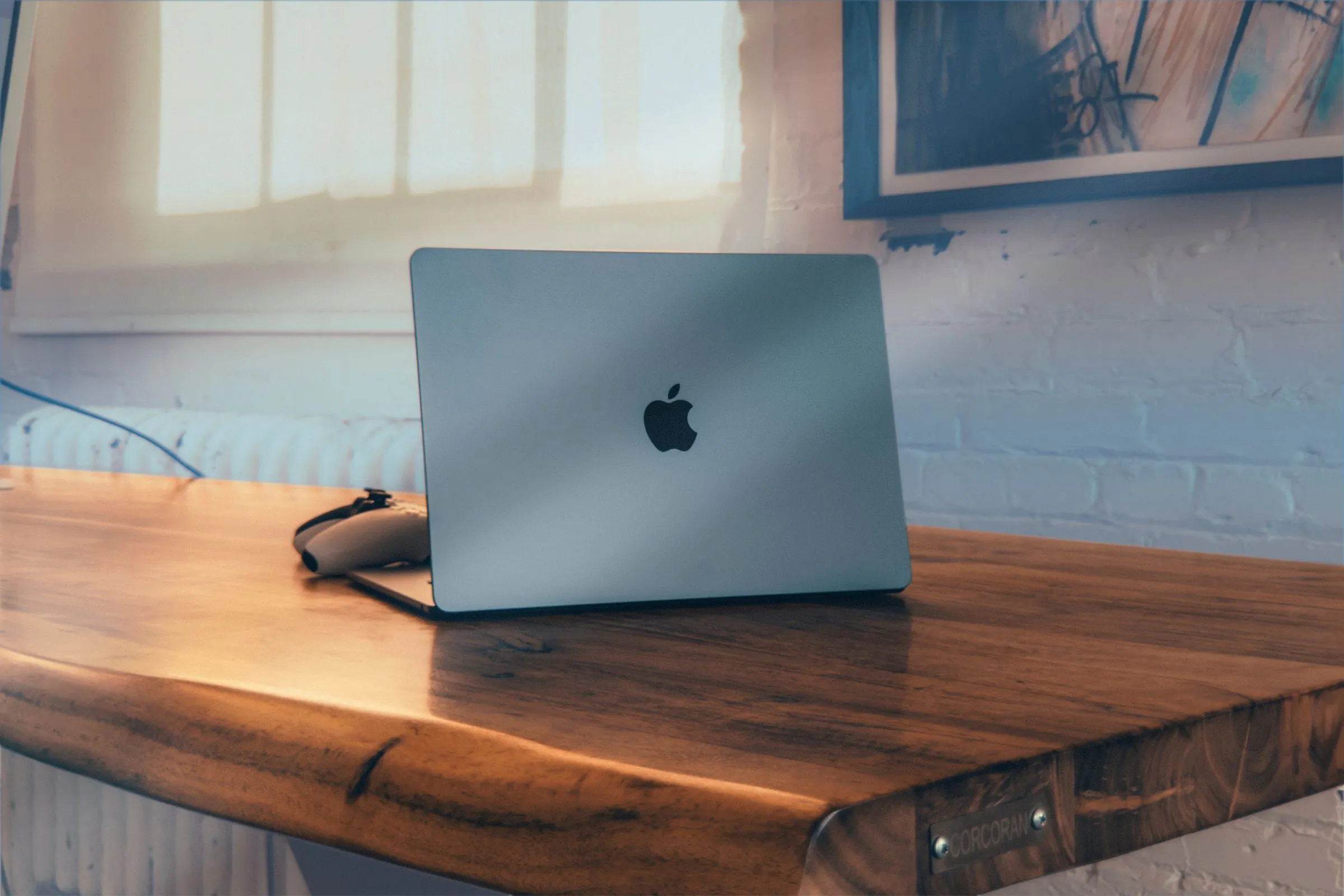 Một chiếc MacBook Air màu bạc đặt trên bàn gỗ.