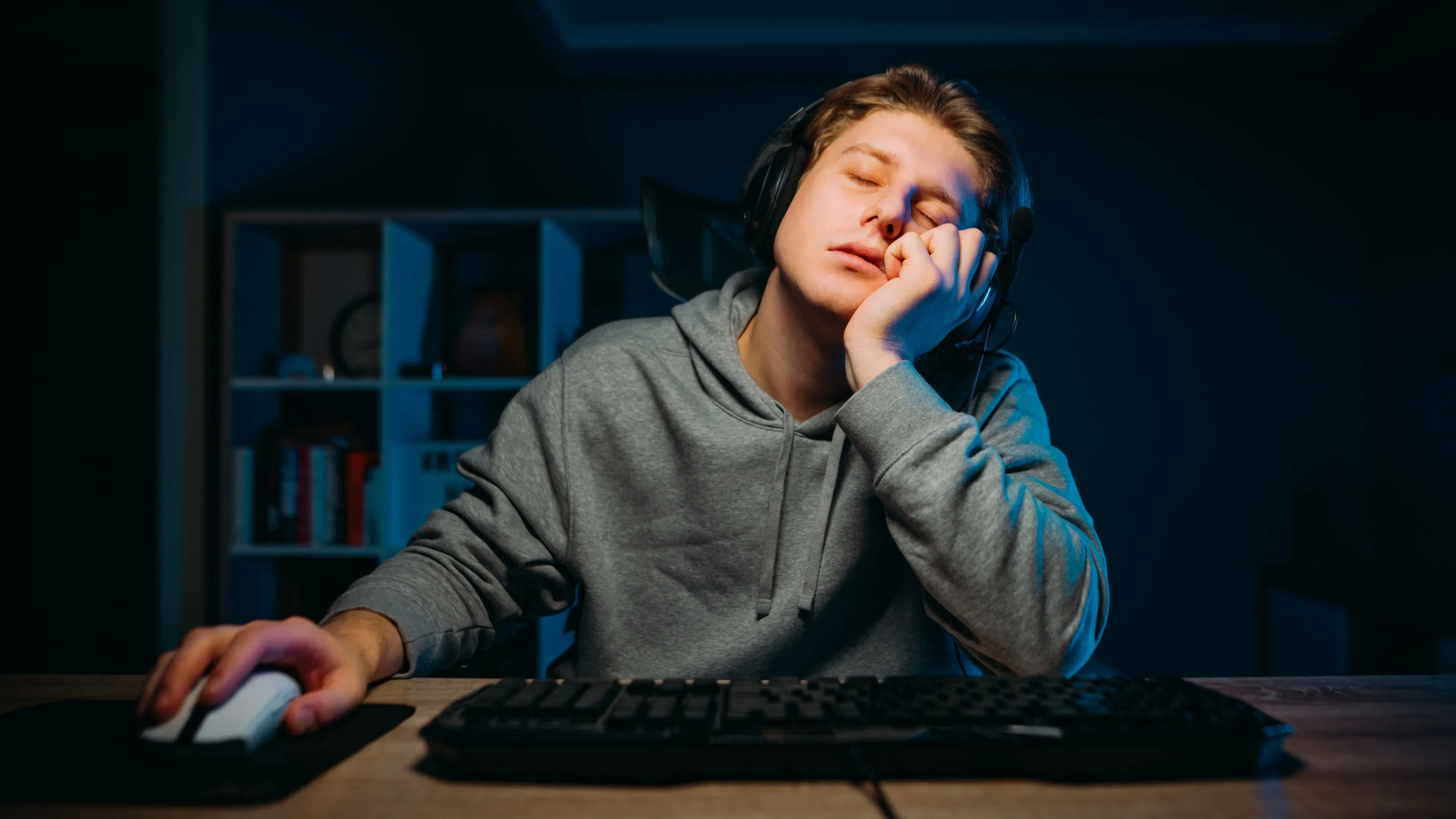 Một game thủ trông có vẻ mệt mỏi và buồn chán ngồi trước máy tính, thể hiện sự thiếu hứng thú do thị trường thiếu cạnh tranh.