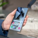 Một người đang cầm điện thoại Samsung Galaxy S24 Ultra hiển thị màn hình chính, minh họa giao diện One UI 6.1 và Always On Display.