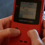 Một người đang chơi game Pokémon Yellow trên máy Game Boy Color cổ điển, minh họa đồ họa và trải nghiệm game xưa.