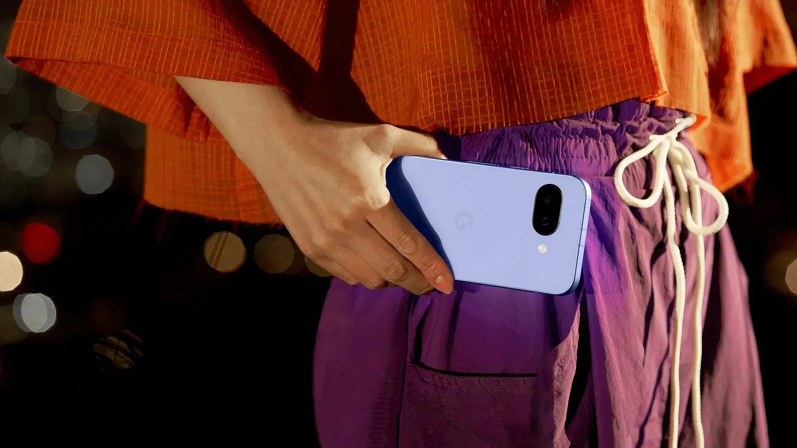 Một người phụ nữ đang cầm điện thoại Google Pixel 9a ở ngang eo, thể hiện khả năng chụp ảnh góc siêu rộng