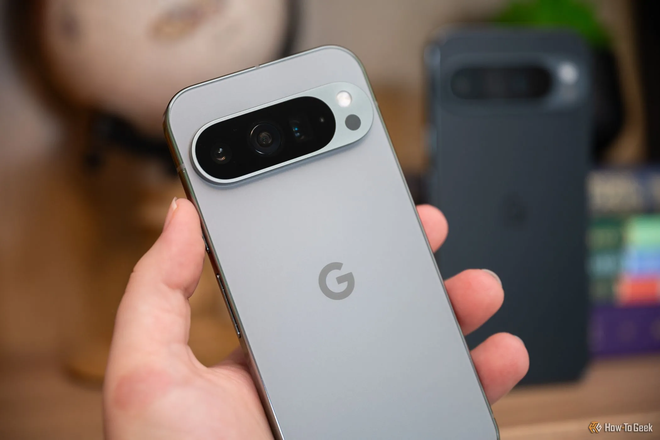 Người cầm điện thoại Google Pixel 9 Pro đứng trước Pixel 9 Pro XL, cho thấy sự khác biệt kích thước và thiết kế camera.