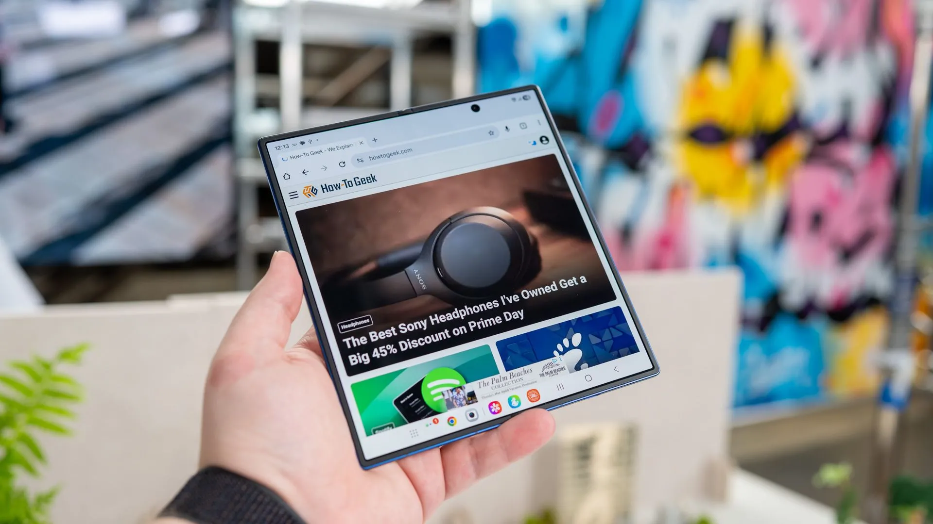 Người dùng cầm điện thoại gập Samsung Galaxy Z Fold 7 đang mở ra, hiển thị trang web How-To Geek trên màn hình lớn.