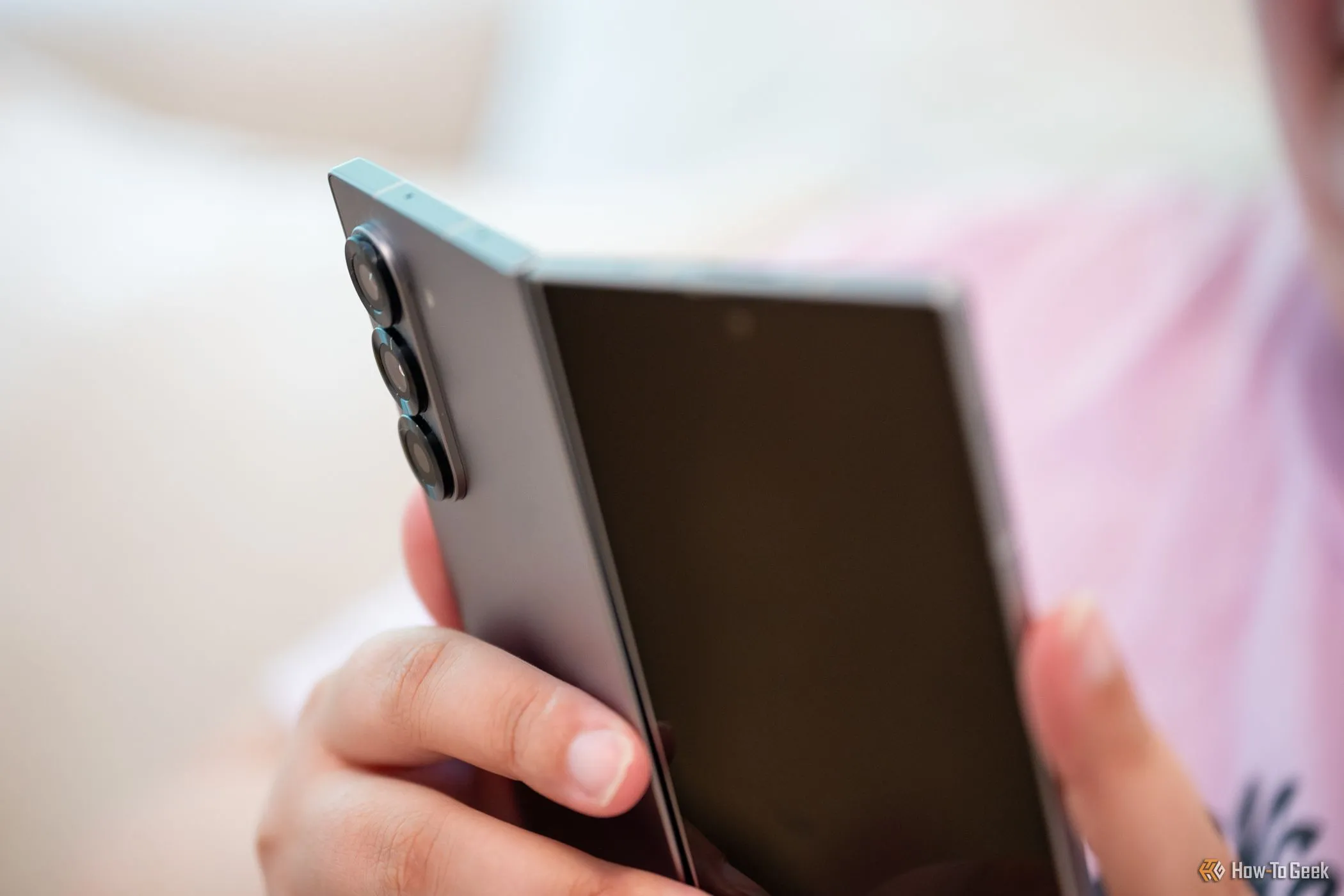 Người dùng cầm điện thoại Samsung Galaxy Z Fold 6 đang mở nhẹ, nhìn vào cụm camera sau, minh họa sự trưởng thành của thiết bị gập