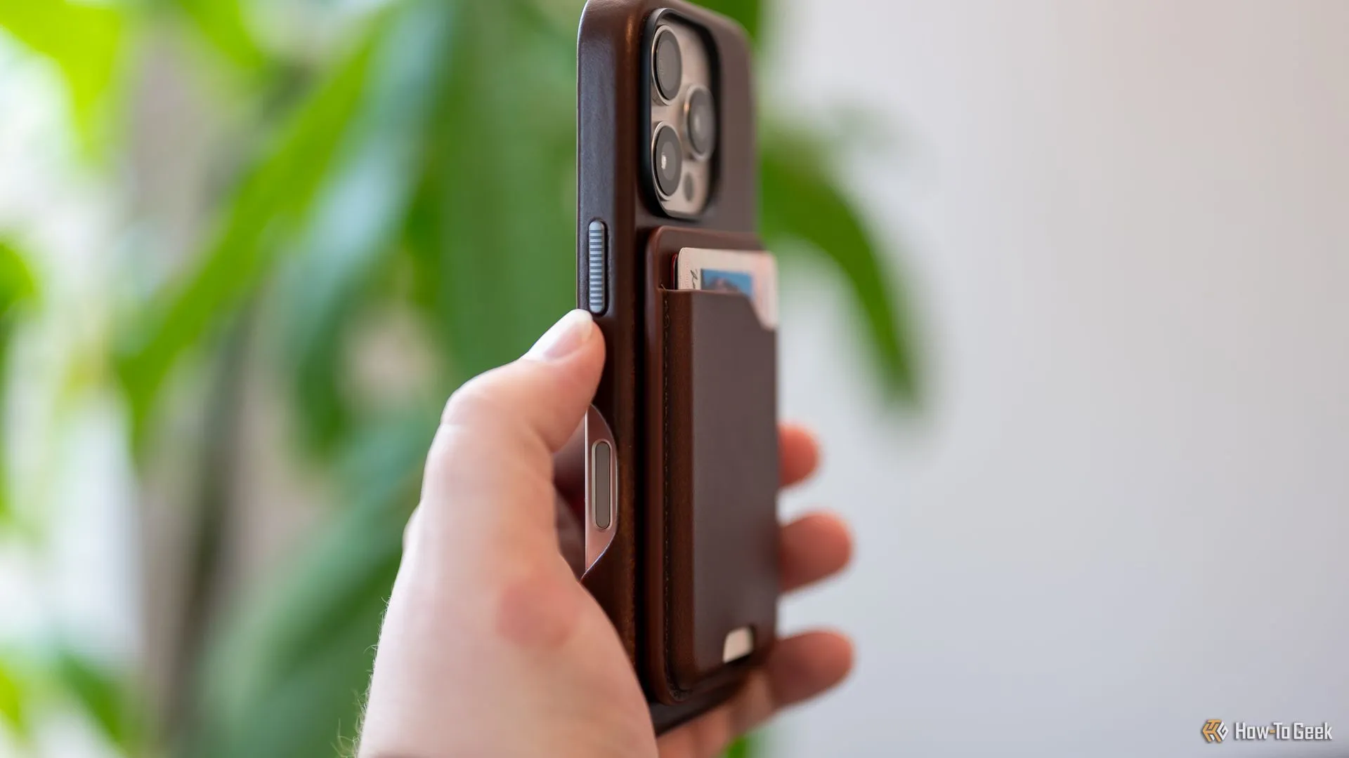 Người dùng cầm iPhone gắn ví Nomad Leather Mag Wallet, thể hiện sự gọn nhẹ và tích hợp liền mạch với điện thoại.