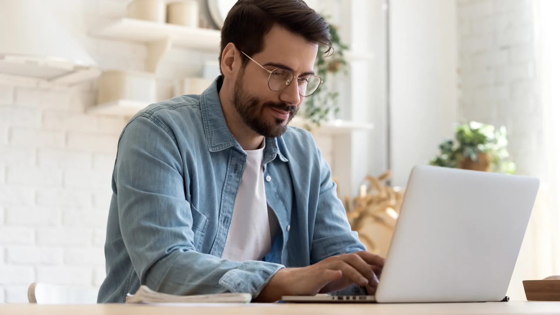 Người làm việc tự do (freelancer) tập trung sử dụng laptop trong bếp hiện đại, minh họa việc tận dụng thời gian rảnh để tăng thu nhập sau khi giảm lướt mạng xã hội.