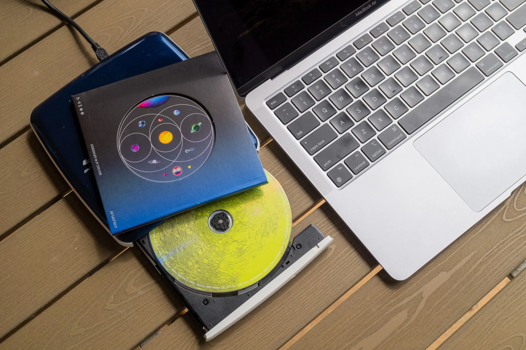 Ổ đĩa CD ngoài và một đĩa CD nhạc cạnh MacBook Air.