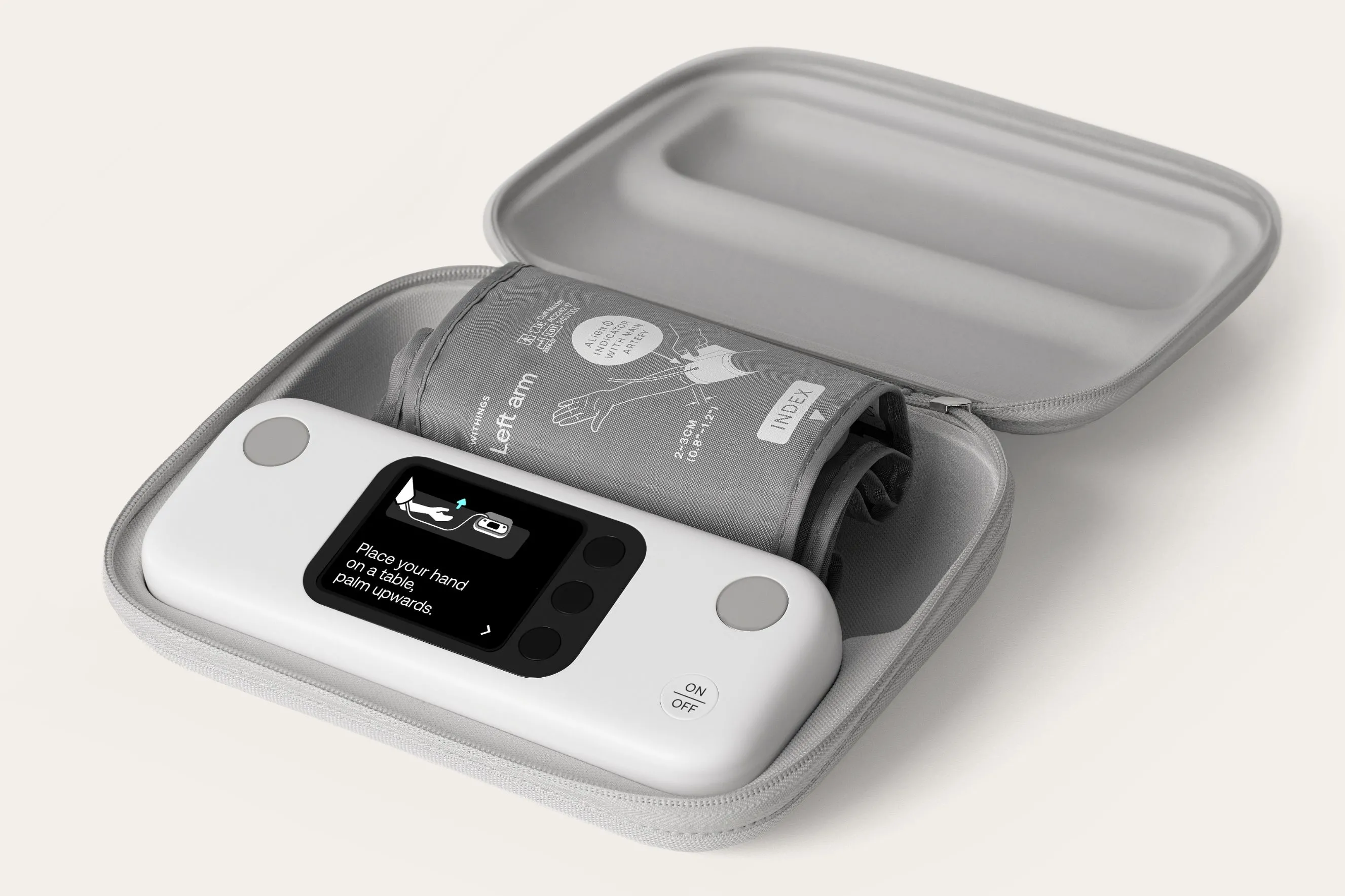 Withings BPM Vision màu trắng đặt bên cạnh vòng bít, với hộp đựng mở ra để lộ các phụ kiện bên trong.